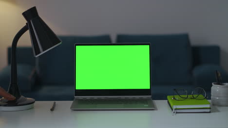 zooming-shot-of-working-place-in-apartment-notebook-with-green-screen-lamp-and-books-for-remote-work-and-using-laptop-interior-of-modern-apartment